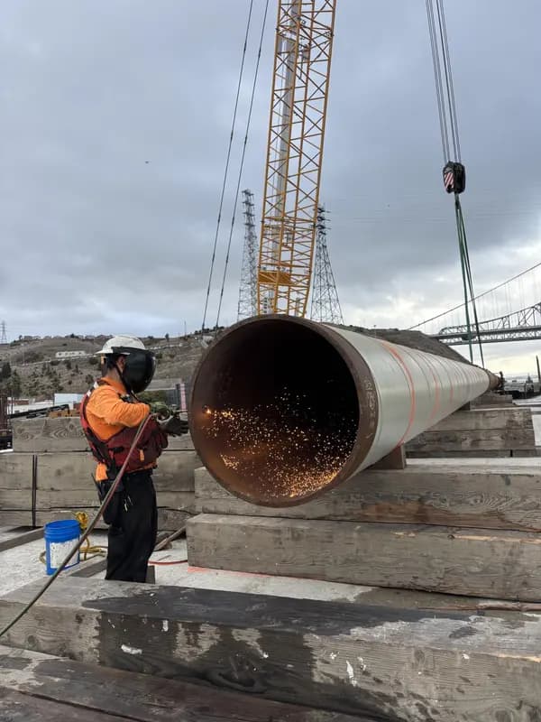 Cutting a large industrial pipe, sparks flying on a job site